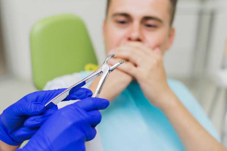 homem com medo de extrair dente com mão de dentista com alicate