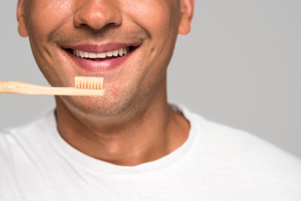 Homem segurando escova sorrindo evitando tártaro nos dentes